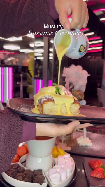 A promotional reel for Rassams Creamery, featuring close-up shots of indulgent desserts being drizzled with sauce, a large milkshake, and the venue's robot server delivering food to a table.