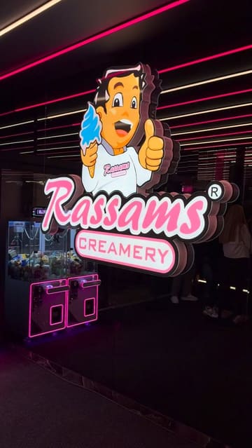 A montage of various indulgent desserts, including a chocolate fondue set, waffles, cakes, and elaborate freakshakes, filmed in a dessert parlour setting with neon lighting.
