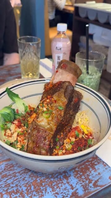 A short video showcasing a visit to Noodle Inn, featuring close-ups of their signature braised beef rib knife-cut noodles, fried wontons, and spring rolls, along with a shot of the restaurant's exterior.