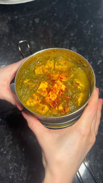 A short video showcasing the unboxing of a DabbaDrop sustainable takeaway meal, featuring the metal tiffin container and the plant-based Indian dishes inside.