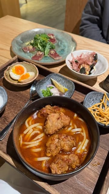 A short review-style reel showcasing a visit to UMI, a Japanese restaurant in Edinburgh. The video features close-ups of various dishes including gyoza, takoyaki, tuna tataki, curry udon, and tonkatsu, alongside shots of the restaurant's interior and the creator enjoying the meal.