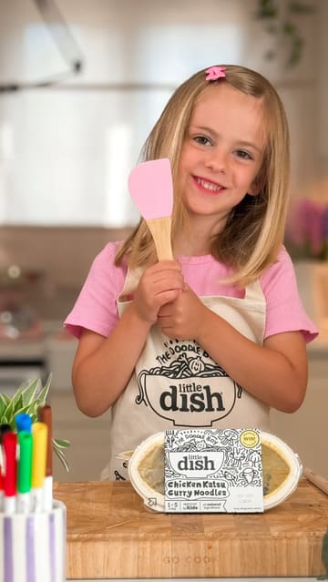 A sponsored video featuring a mother and her two children preparing and eating a 'Little Dish' branded chicken katsu curry meal, highlighting the product's ease of use and the included colouring competition.