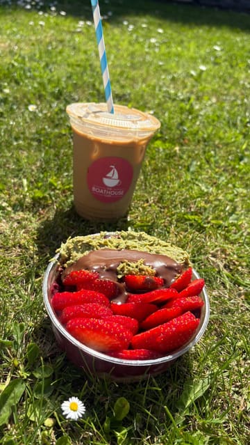 A creator visits The Boathouse Cafe in Antrim, Northern Ireland, to review their açai bowls. The video features shots of the scenic waterside location, the cafe's exterior, the menu, and a taste test of the 'Dubai' açai bowl and an iced latte.