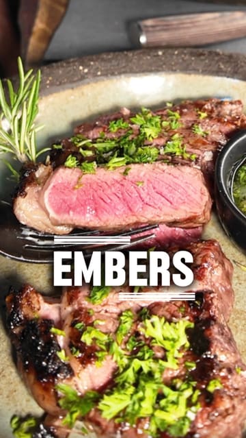 A couple visits Embers restaurant, showcasing their 'Embers Feast' set menu. The video features close-up shots of various dishes including sourdough, grilled broccoli, lamb sausage, sirloin steak, and a Rolo-themed dessert, interspersed with clips of the cooking process and the couple enjoying their meal.