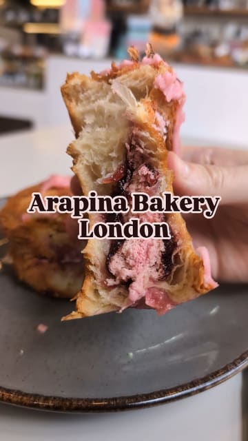 A short, visual-focused reel showcasing two pastries—a raspberry scroll and a cookie croissant—being pulled apart and cut, alongside an iced coffee, at a bakery.