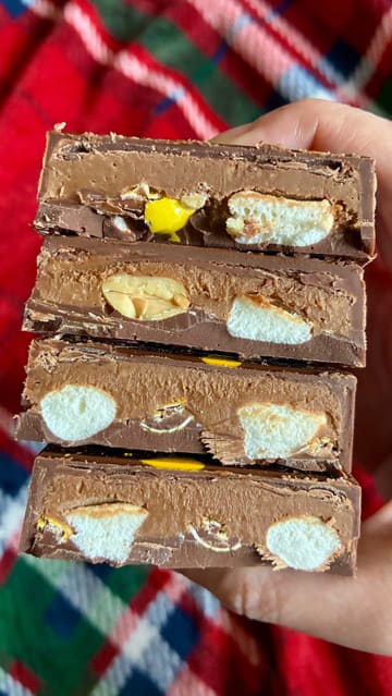 A short, punchy video showcasing two large, filled chocolate bars from the brand Achocco. The video features close-up shots of the bars being broken open to reveal the peanut butter truffle and pistachio kunafa fillings.