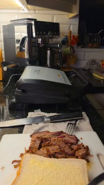 A short, handheld video demonstrating the preparation of a brisket toastie using a contact grill at home.