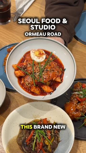 A video review of Seoul Food & Studio on Ormeau Road, featuring two creators trying various Korean dishes including fried chicken, tteokbokki, japchae, and black sesame ice cream. The video highlights the food, the interior, and the overall dining experience.