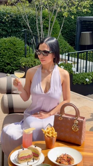 A high-quality, aesthetic video showcasing the terrace at Bar Antoine, located at the Four Seasons Hotel London. The video features a woman enjoying cocktails and small plates in a sunny, upscale outdoor setting, highlighting the sophisticated atmosphere and the pétanque game available on the terrace.