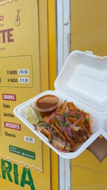 A short promotional video for a food truck called Mucho Picante, featuring close-up shots of their birria tacos being dipped in consommé, alongside a view of their menu board and drink selection.
