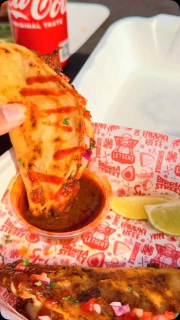 A short promotional video for a food truck called Letseat, showcasing their birria tacos and birria pizza, including close-ups of the food and dipping action.