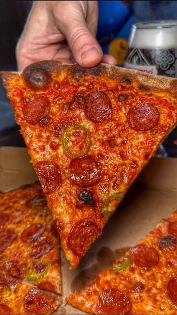 A short, energetic review of a small pizza takeaway operating out of a former taxi office in Manchester, highlighting the limited menu and the option to take the pizza to a nearby pub.