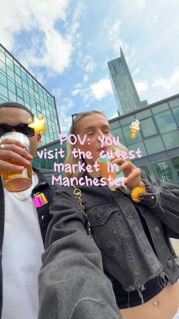 A couple spends a day at Campfield Market in Manchester, showcasing various stalls including a bakery, a sticker machine, art prints, and Caribbean street food. The video uses a chronological timestamp format to guide the viewer through their experience, highlighting the food, drinks, and shopping opportunities available at the market.