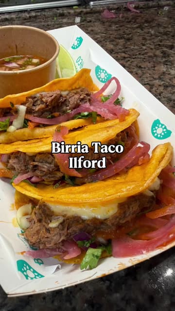 A high-energy review of Birria Taco's return to East London at the Maison Noor food hall, featuring close-ups of their signature birria tacos, ramen, loaded nachos, and elote.