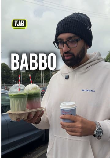 The creator visits Babbo, a cafe in Glasgow, to review their coffee and drinks. He provides a personal assessment of the matcha and flat white, while also giving a brief tour of the venue's interior and outdoor seating area.