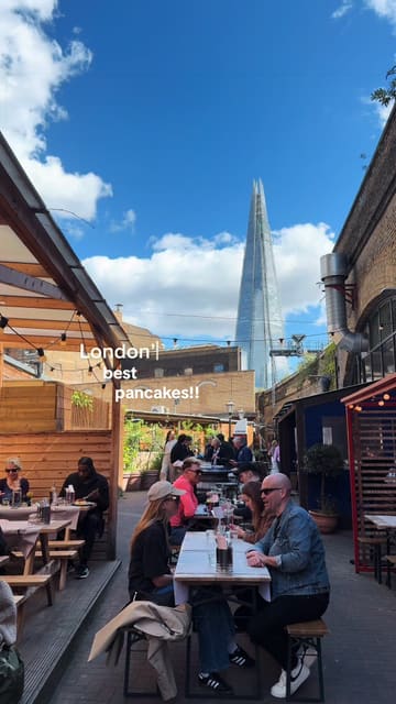 A short, engaging video showcasing a brunch venue in London, highlighting their pancake menu, including a special chocolate collaboration and classic bacon and blueberry options. The video features shots of the food, the menu, and the venue's outdoor and indoor seating areas.