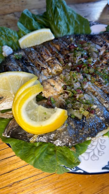 A montage showcasing the interior, menu, and various Greek dishes at Acropoli in Merthyr, including meze, whitebait, grilled fish, and a chicken gyro platter.