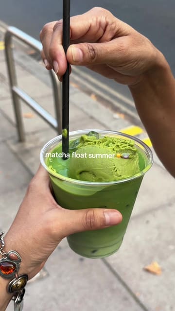 A short, handheld clip featuring a matcha float being stirred and sampled. The video focuses entirely on the drink, showcasing the texture of the matcha ice cream and the drink itself.