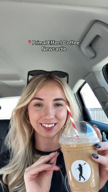 The creator visits Primal Effect Coffee in Newcastle, Northern Ireland, sharing their experience of trying an iced oat vanilla latte and a Biscoff protein ball. The video features the creator talking to the camera, shots of the coffee and food, and a brief look at the venue's outdoor seating area.