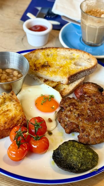 A short, punchy montage of breakfast dishes at a cafe, featuring close-up shots of a breakfast muffin being pressed, coffee, a full breakfast plate, and a Dutch pancake.