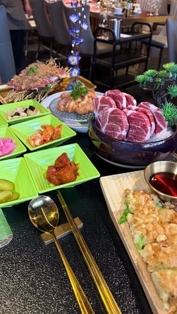 A short, energetic video showcasing a Korean BBQ restaurant, featuring close-ups of bibimbap, spring onion pancakes, various raw meats for grilling, and cocktails. The video captures the interactive nature of the dining experience and the venue's interior.