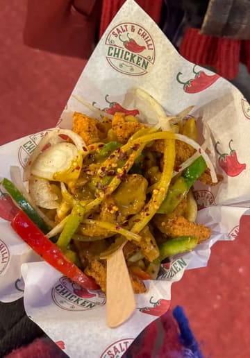 A short, engaging video featuring a creator visiting a Salt & Chilli Chicken stall at the Edinburgh Christmas market. The video shows the stall, the food being served, and the creator trying the dish.