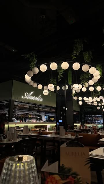 A montage video showcasing a visit to Aurelia, featuring shots of the restaurant interior, a sharing platter, cocktails, a Wagyu steak, pasta, and tiramisu.