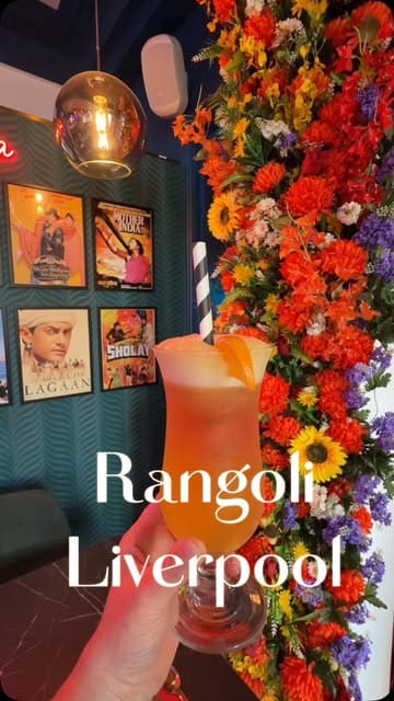 A promotional video for Rangoli in Liverpool, featuring a montage of the restaurant's interior, specifically highlighting its Indian cinema-themed decor, alongside shots of various dishes including prawns, curries, and a mocktail.