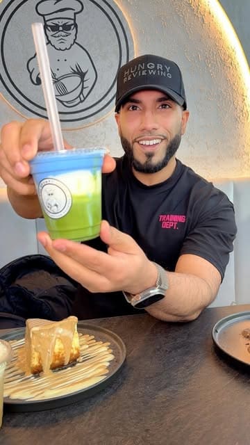 A creator visits the new flagship store of The Grumpy Baker in Manchester to review their cheesecakes and drinks, highlighting the interior and specific menu items.