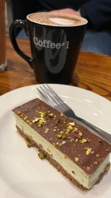 A short, handheld-style video showcasing a visit to a Coffee#1 branch, highlighting their winter drink and cake selection, including a pistachio slice and pecan pie.