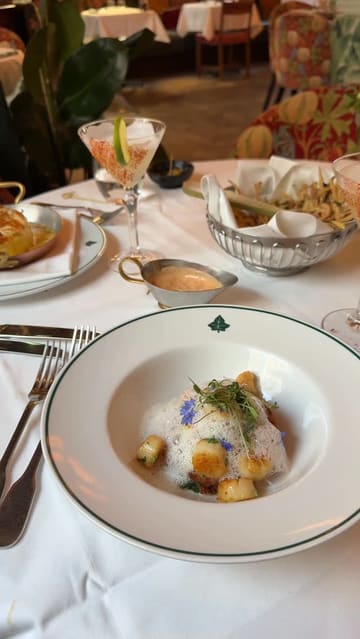 A first-person vlog review of The Ivy in Exeter, featuring a date night experience. The video captures the exterior, the interior ambiance, a variety of cocktails, and several courses including gnocchi, lobster risotto, salmon, and desserts like creme brulee and cookie dough.
