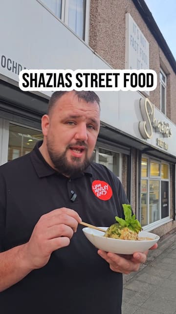 A food review video featuring a creator visiting Shazias Street Food in Bury to try their unique Pakistani-style Scotch egg. The video includes shots of the kitchen, the food preparation, and the creator's reaction to the dish.
