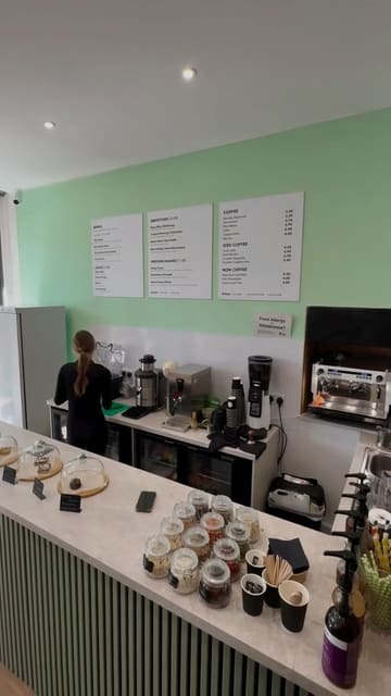 A promotional video for The Hundred Bar, featuring close-ups of their acai bowls, protein shakes, and coffee menu, highlighting the fresh preparation and variety of healthy options available.