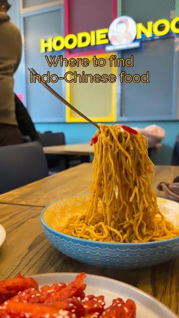 A quick-cut montage showcasing various Indo-Chinese fusion dishes, including hanging noodles, dumplings, and customizable box meals at a casual restaurant.