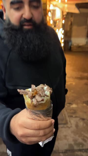 A creator visits Tarbushi Shawarma, a street food stall, to review their lamb shawarma wrap. The video features the creator talking to the camera, interacting with the staff, and showing the preparation and consumption of the food.