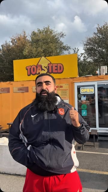 A creator visits a street food venue called Toasted in Birmingham to review their Philly cheesesteak. The video follows the creator as they order, interact with staff, and taste the food, providing an authentic review of the experience.