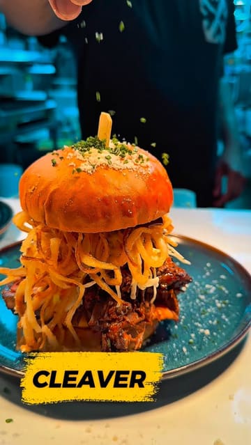 A promotional video showcasing the menu and interior of Cleaver, a Canadian-themed restaurant in Manchester, featuring close-ups of burgers, steak, mac and cheese, and milkshakes.