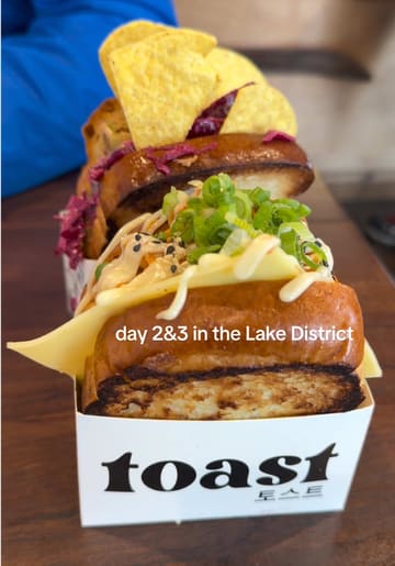 A personal travel vlog documenting a two-day trip to the Lake District, featuring accommodation in a cabin, boat hire on Lake Windermere, a visit to a sandwich shop called Toast, a Christmas shop, and an ice cream parlour.
