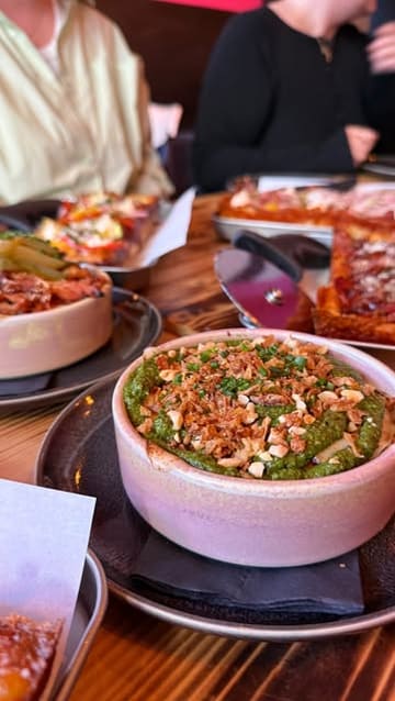 A vlog-style video showcasing a food tour at Princesshay in Exeter, visiting Yo! Sushi for conveyor belt sushi, Pop Kitchen for Detroit-style pizza and sides, and Chandos Deli for sweet treats.