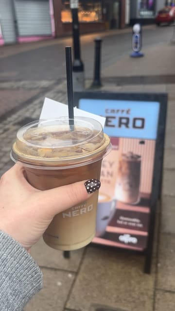 A short vlog-style review of the new Honey Oat Pecan Latte at Caffè Nero. The creator visits the cafe, shows the drink, the coffee machine, the pastry display, and the exterior of the venue, providing a positive review of the drink's taste and value.