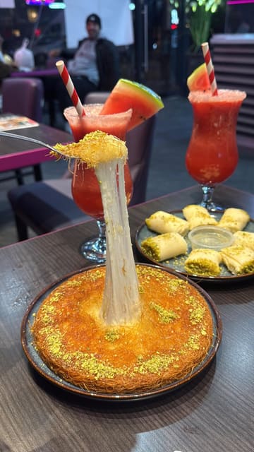 A short, visually focused reel showcasing the preparation and serving of fresh Kunafah at Mandi & Sweet House in Glasgow. The video features close-up shots of the cheese pull, the cooking process, and the final plated dessert alongside fresh fruit juices.
