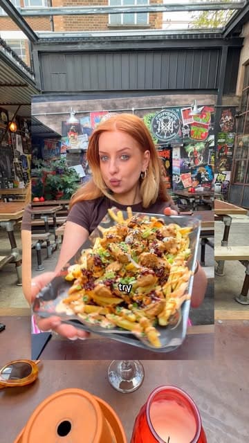 A vlog-style review of a bottomless vegan chicken experience at Saint Monday brewery in Hackney, featuring loaded fries with various toppings and hot sauce.
