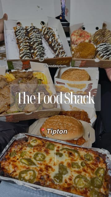 A fast-paced montage showcasing various takeaway items from The Food Shack, including a spicy chicken burger, donner stir fry, beef cheese bake, donuts, and waffle sticks. The video focuses on close-up shots of the food to highlight textures and ingredients.