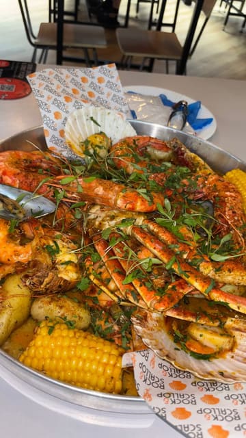 A promotional video for 'Rock & Scallop' featuring their signature seafood boil. The video showcases the preparation and presentation of the large platter, the creator enjoying the meal, and shots of the venue's interior and exterior at Newport Market and Albert Hall, Swansea.