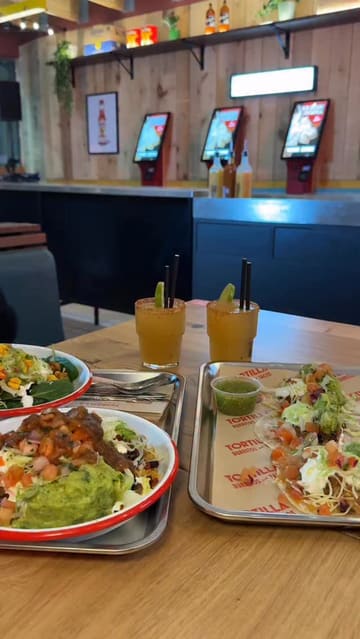 A short, energetic vlog-style video showcasing the opening of a new Tortilla restaurant in Leeds. The video features the creator trying various dishes, including burrito bowls and tacos, as well as spicy margarita slushies. It highlights the venue's interior, the ordering counter, and the lively atmosphere with a DJ.