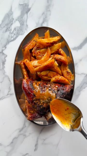 A recipe tutorial video demonstrating how to prepare a slow-roasted harissa lamb dish with roasted potatoes, tzatziki, and a Greek salad, using ingredients from Sainsbury's.