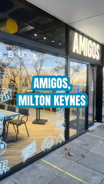 A short video showcasing the interior and menu offerings of Amigos Burgers in Milton Keynes, featuring close-ups of a chicken burger, a milkshake, and loaded churros.