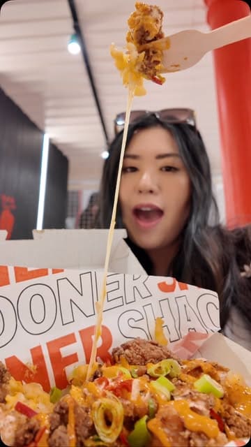 A creator visits the new Doner Shack location in Glasgow, documenting the experience from the ordering kiosks to the final meal. The video features close-ups of various menu items including loaded fries, chicken tenders, and a milkshake, alongside shots of the venue's interior and seating area.