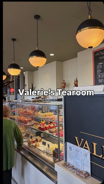 A vlog-style review of a visit to Valerie's Tearoom after a Sunday run, featuring a look at the cake display, the interior, and a taste test of a chicken caesar wrap, corned beef pie, and chocolate cake.