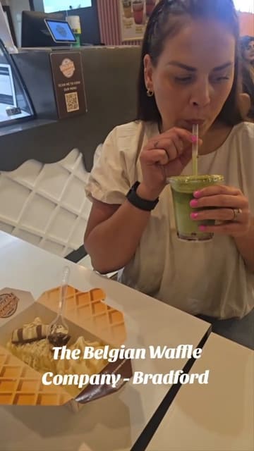 A vlog-style review of The Belgian Waffle Company in Bradford, featuring the creator and their children trying various dessert items including waffles, milkshakes, and brownies. The video highlights the interior decor, the extensive menu, and the family-friendly experience.